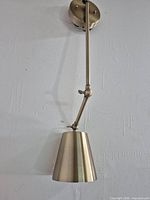 Full view of wall sconce showing mounting plate, adjustable arm and cone shade
