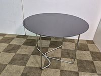 Full view of Natuzzi round table showing dark glass top and stainless steel base