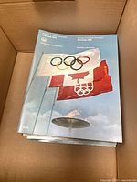 Stack of Montreal 1976 daily programs showing opening ceremony cover with flags and cauldron