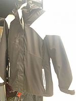 Black and white Karbon ski jacket hanging, front view showing full zipper and pockets
