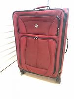 Front view of American Tourister burgundy wheeled suitcase showing pockets and handles
