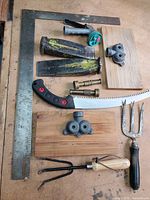 All tools laid out including framing square, wedges, pruning saw, hand tools, hose parts