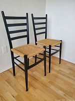 Two black ladder-back chairs side by side, full view