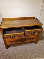Front view with two top drawers open showing carved fronts and bottom drawer closed