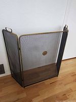 front view of brass fireplace screen with mesh and medallion