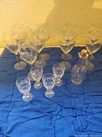 All nine wine glasses, four sherry glasses and glass cruet on fabric backdrop