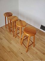 Four pine bar stools side view on wood floor