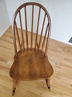 Front view of vintage solid wood rocking chair showing spindle back and contoured seat