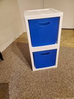 Two stacked white plastic cubes with blue drawers