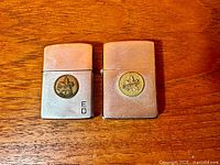 Front view of both Zippo lighters showing emblems and finish