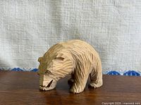 Left side view of hand-carved wooden bear figurine on tabletop