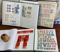 Four albums open showing variety of Canadian stamps on pages including red Lunar New Year panes and rows of older definitives