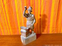Full view of entire wood sculpture showing blacksmith figure on rectangular base