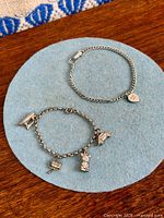 Both bracelets displayed flat to show overall design and charms