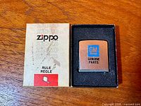 Item in open box showing front plate with GM logo and Zippo Rule packaging