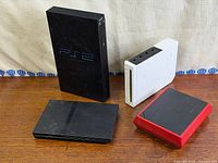 All four consoles grouped: PS2 fat, PS2 slim, Wii white, Wii Mini red