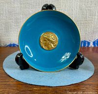 Front view of teal dish showing gold relief and gilt rim on stand
