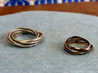 Both sterling silver interlocking rings side by side showing overall design and patina difference