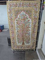Full view of tapestry on stand showing entire design and fringe