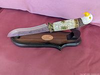 Decorative eagle head knife on wooden stand showing full blade, handle detail and plaque