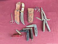 Overview of all knives and tools laid out on red cloth