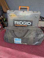 Ridgid hard case atop black fabric tool bag