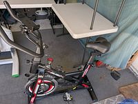 Left side view showing frame, branding, flywheel, pedals, seat and handlebar