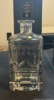 Front view of square cut crystal decanter with stopper, box visible