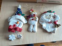 Front view of three resin ornaments: snowman, teddy bear, Santa