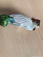Full view of glass bird ornament showing white body and green tail