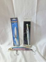 Close-up of Pucci jig in package, Joe Baggs Swarter in box, loose jerkbait front