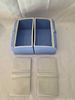 Two blue rectangular dishes without lids, lids placed below