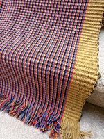 Overall view of runner rug draped showing multicolour stripes, yellow border and fringe