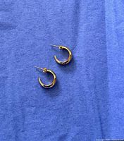 Pair of Mejuri gold vermeil chunky dome hoop earrings on blue cloth