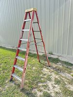 Full view of red fiberglass 8 ft A-frame ladder standing outdoors