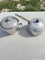 Both aluminum pots with lids shown side by side