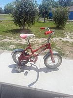 Side view of full bicycle showing frame, wheels, training wheels and accessories