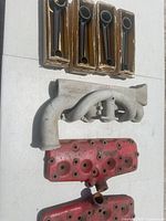 Overview of all parts: four boxed connecting rods, aluminum intake manifold, two red cylinder heads