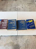 Four automotive manuals arranged side-by-side on a table