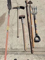 Lineup of seven hand tools on concrete showing overall condition and variety