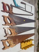 Four panel saws, two hacksaw frames, yellow miter box on table