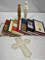 Group shot of eight books, two Madonna figurines and enameled wall cross