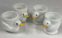 Four bird-shaped milk glass egg cups, front view