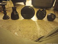 Five black glossy ceramic decor pieces lined up on floor