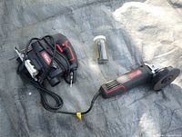 Angle grinder, jigsaw, and jar of bits laid out on tarp