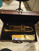Open trumpet case showing trumpet, mouthpiece, cleaning cloth pack