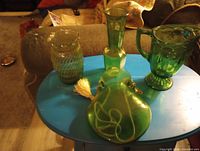 Four green pressed glass vessels on small table