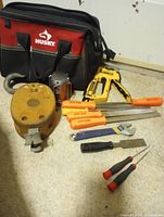 All items laid out: Husky bag, DeWalt stapler, wooden pulley, lantern, assorted files/chisels, screwdrivers