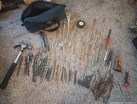 Lot overview on carpet showing tool bag, drill bits, hand tools