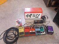 Overall lot showing pedalboard with pedals, boxed Tascam mic set, tuner and cable